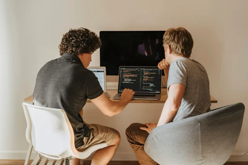 Two developers working through code together on laptops