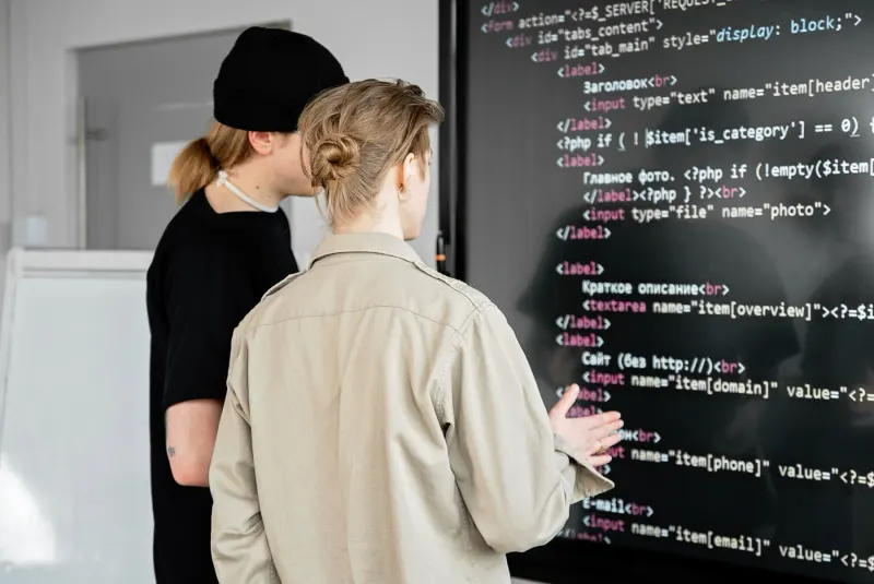 Two developers reviewing code on a large screen